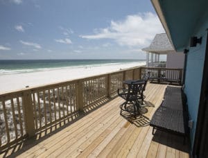 Wooden deck facing beach with brown wicker seating and table